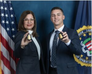 Supervisory Special Agent Marilyn Santos and Special Agent Kevin Vázquez, both of FBI San Juan, pose for a photo with their badges in front of the American flag and the FBI flag.